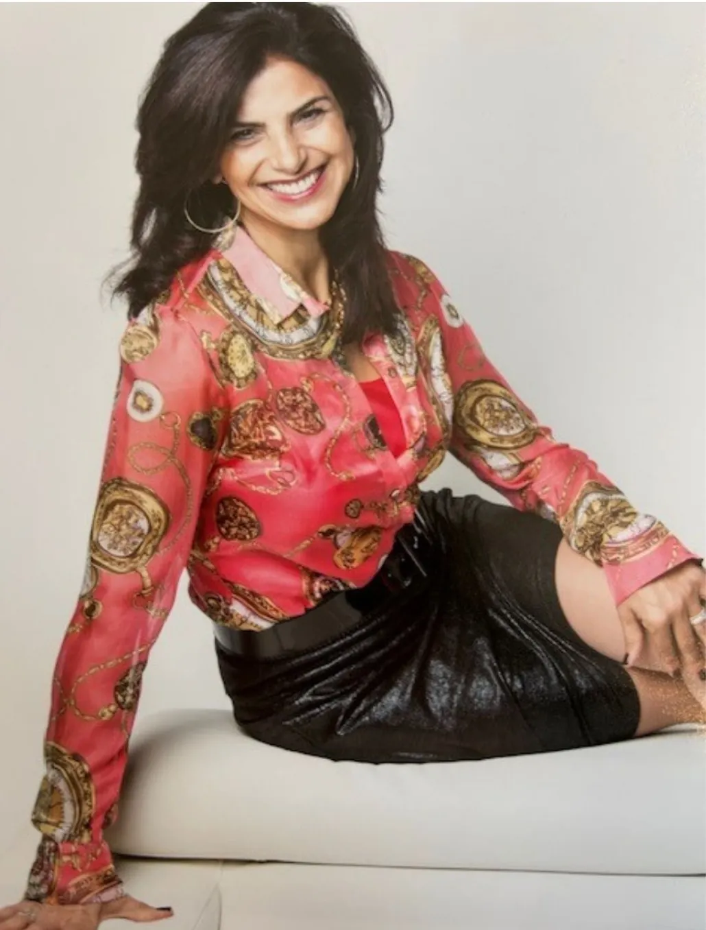 Arielle Innou Nahmias, smiling, seated in a red silk blouse