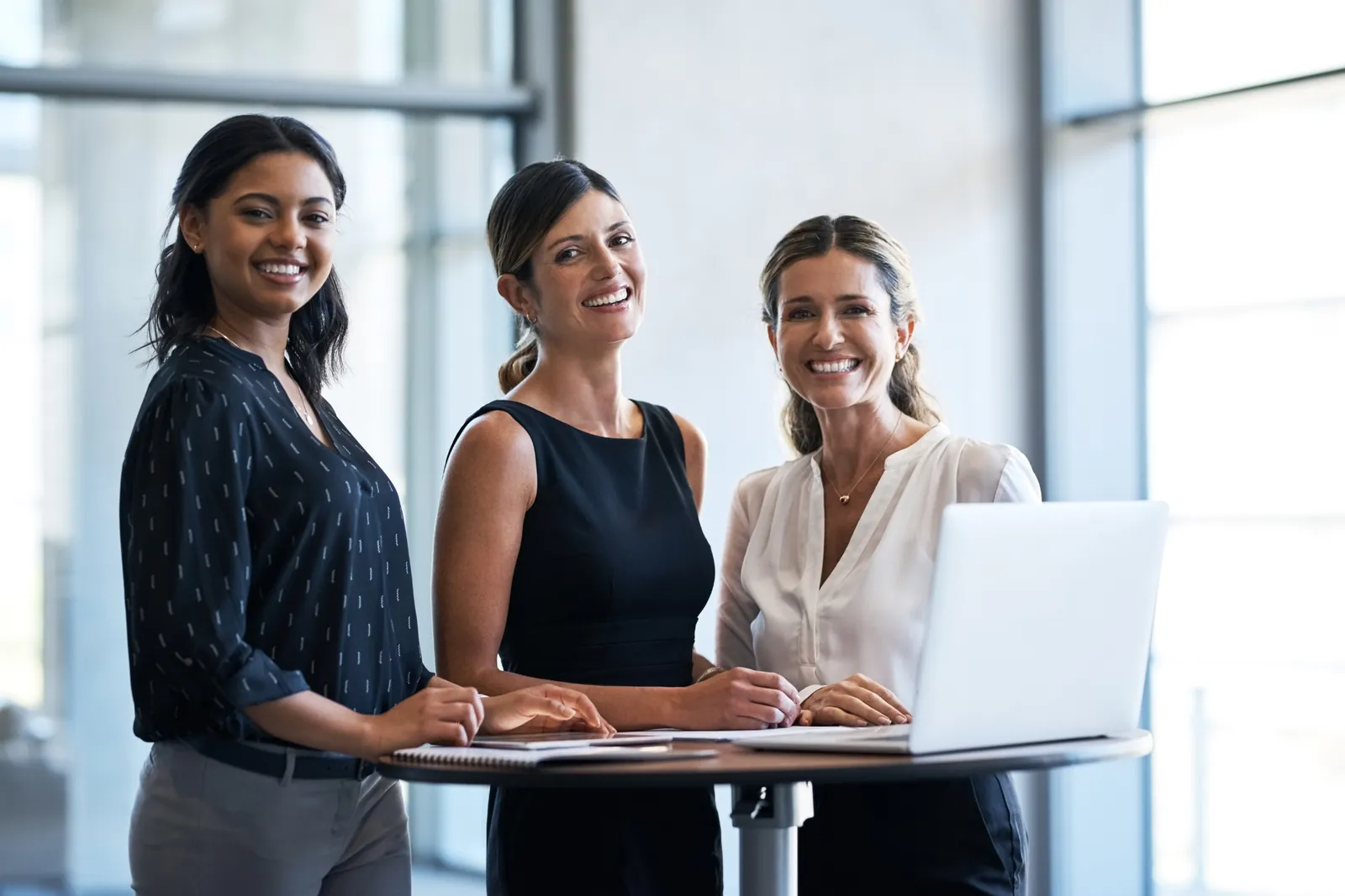 Three smiling professional women at a meeting table