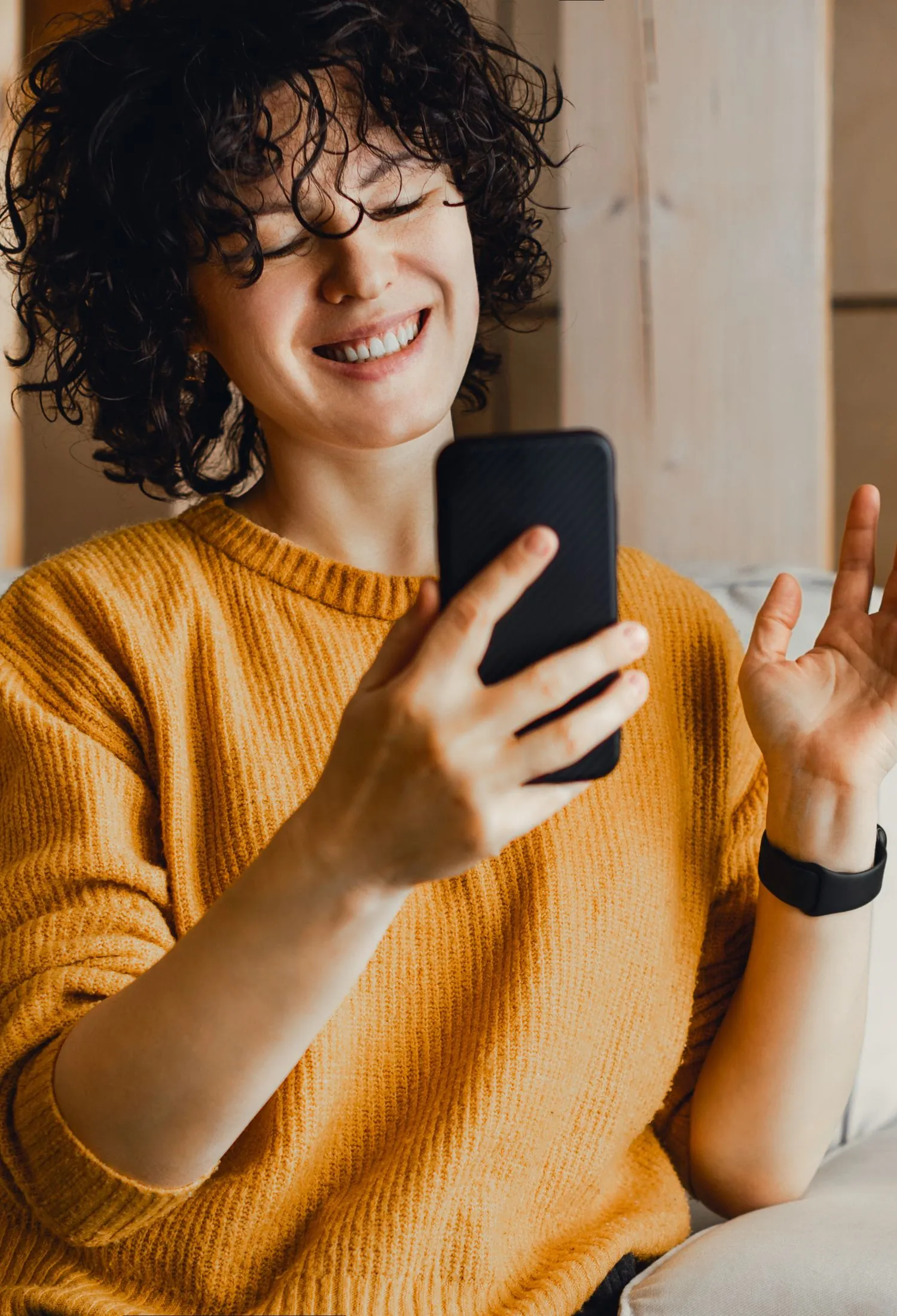 A woman laughing as she reads a message on her phone