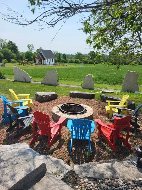 Colourful Muskoka chairs around the fire pit, with the chapel beyond