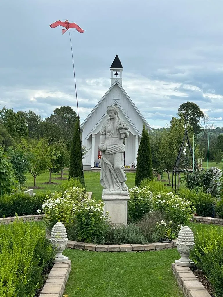 A garden statue in front of the white estate chapel